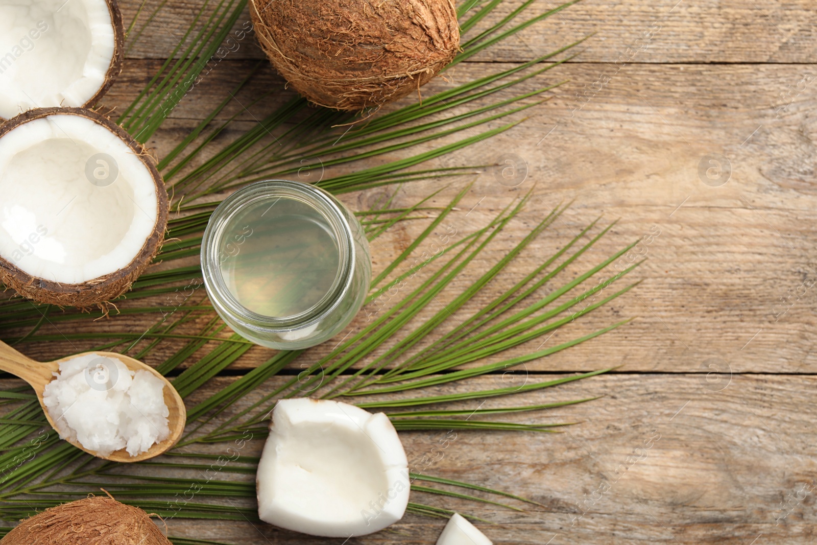 Photo of Flat lay composition with coconut oil on wooden table, space for text