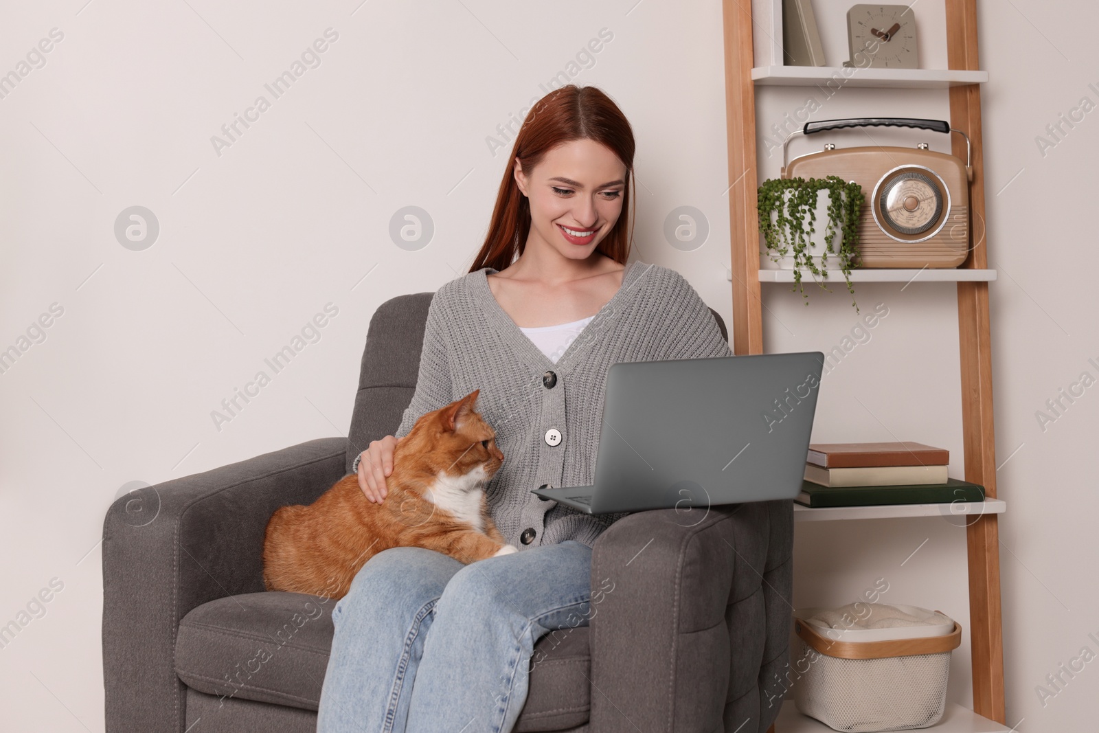 Photo of Happy woman with cat working in armchair at home