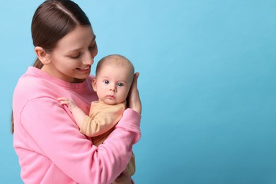 Photo of Happy mother with her cute baby on light blue background, space for text