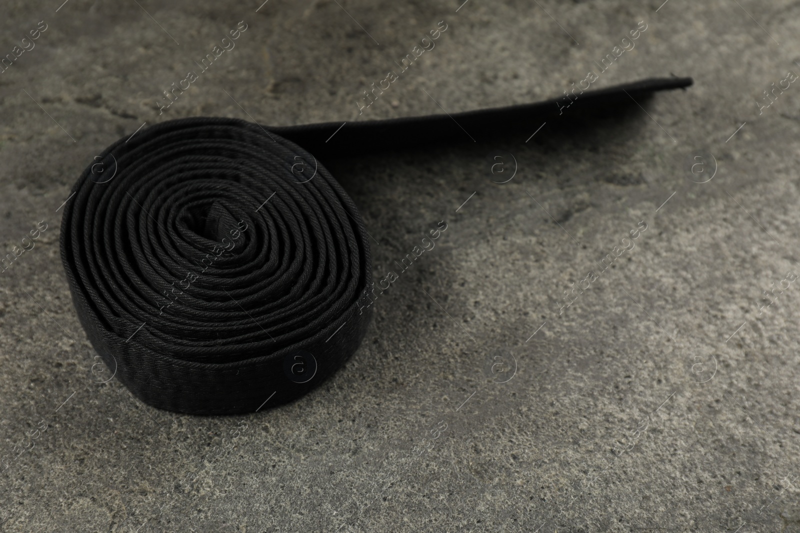 Photo of Black karate belt on gray textured background, space for text