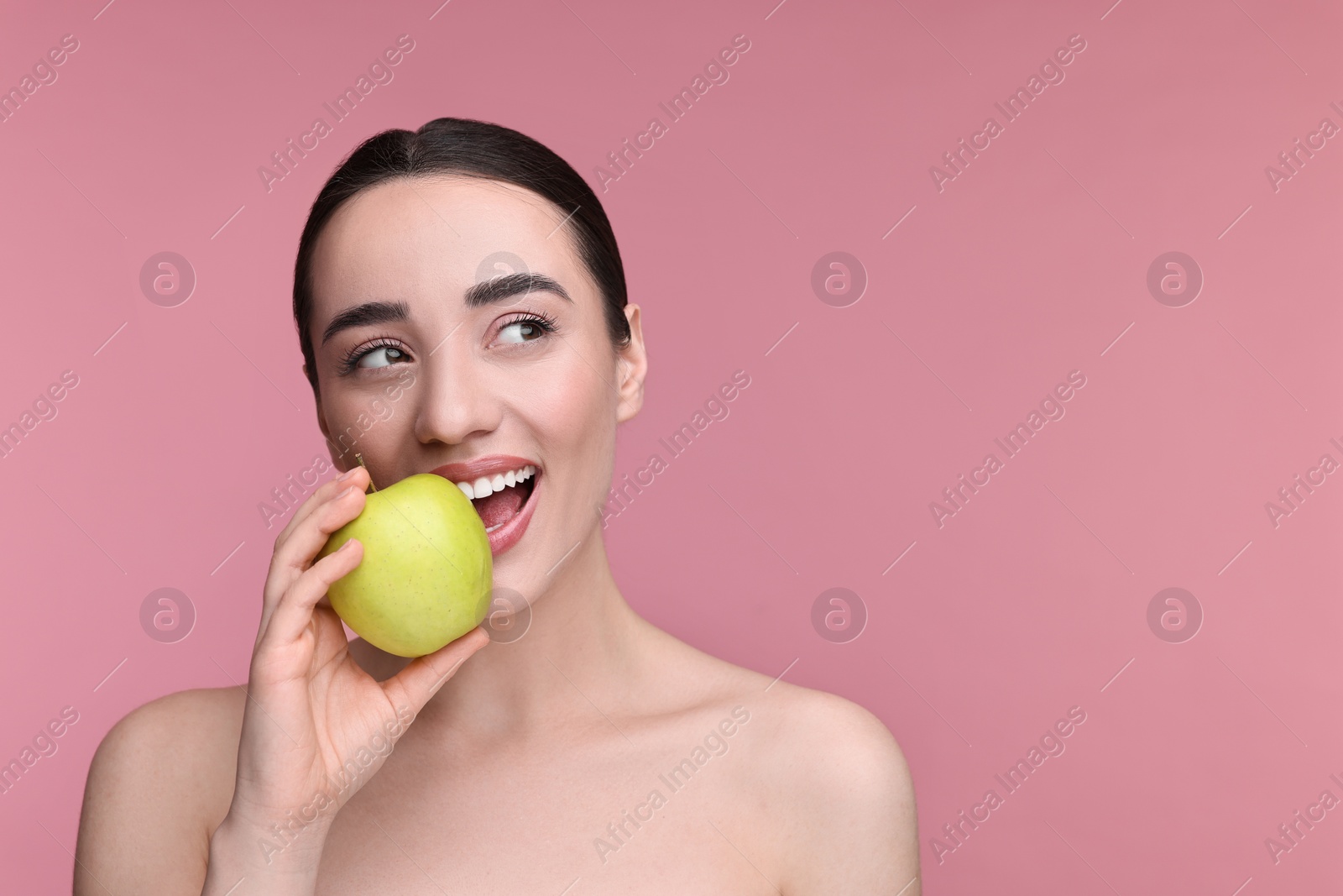 Photo of Beautiful young woman with apple on pink background. Space for text