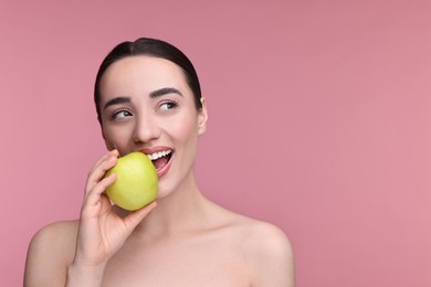 Beautiful young woman with apple on pink background. Space for text