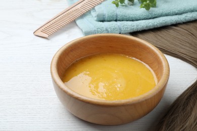 Photo of Homemade hair mask in bowl on white wooden table