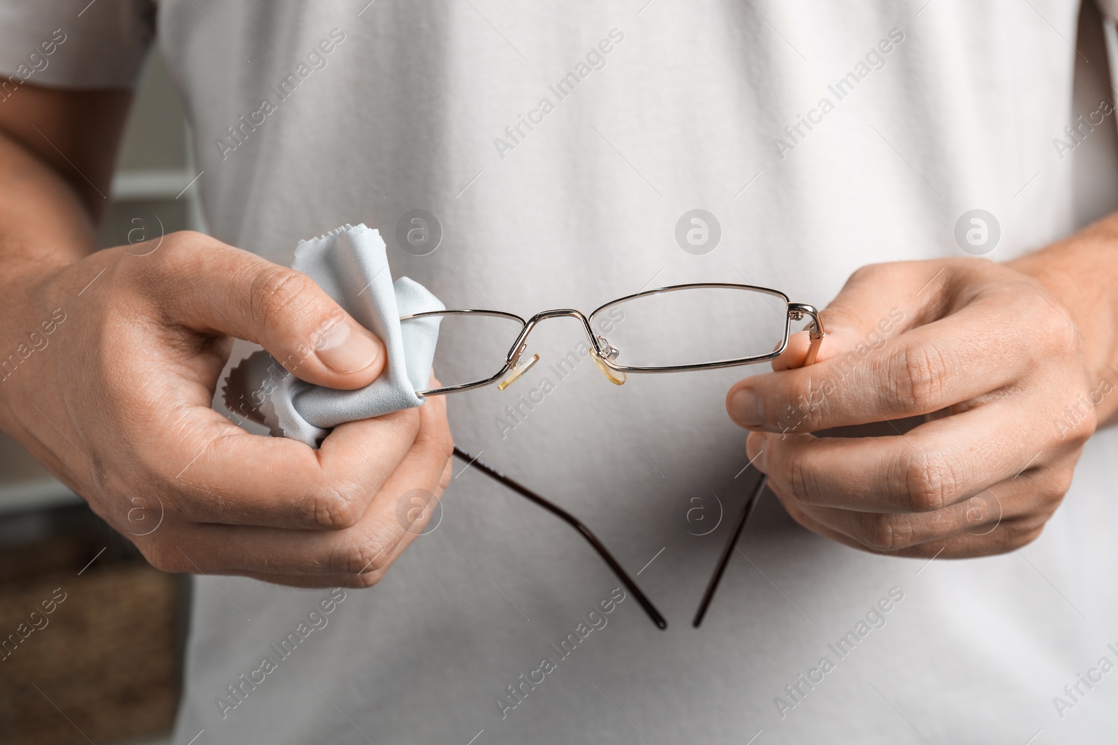 Photo of Man wiping glasses with microfiber cloth, closeup