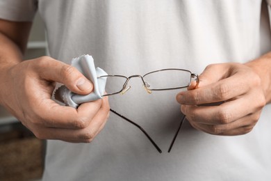 Photo of Man wiping glasses with microfiber cloth, closeup
