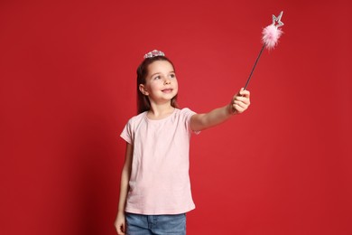 Photo of Cute girl in diadem with magic wand on red background. Little princess