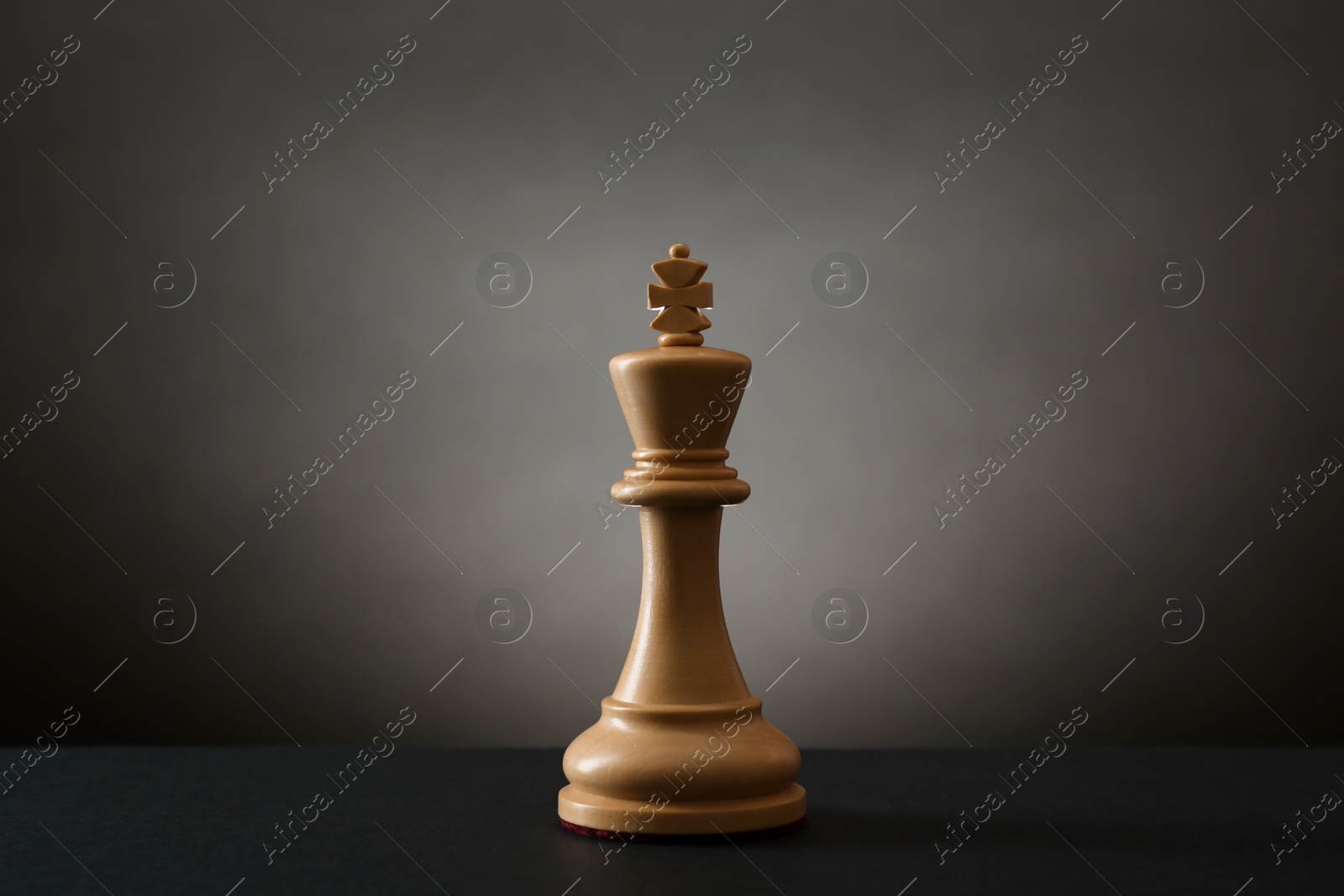 Photo of Wooden king on table in darkness. Chess piece