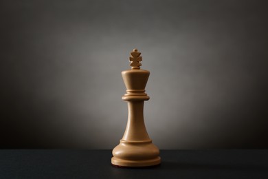 Photo of Wooden king on table in darkness. Chess piece
