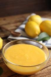 Photo of Delicious lemon curd in glass bowl on wooden table
