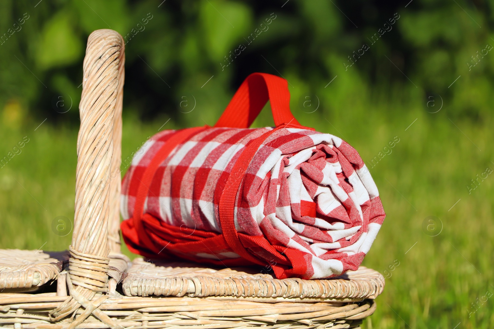 Photo of Checkered tablecloth on picnic basket outdoors, closeup