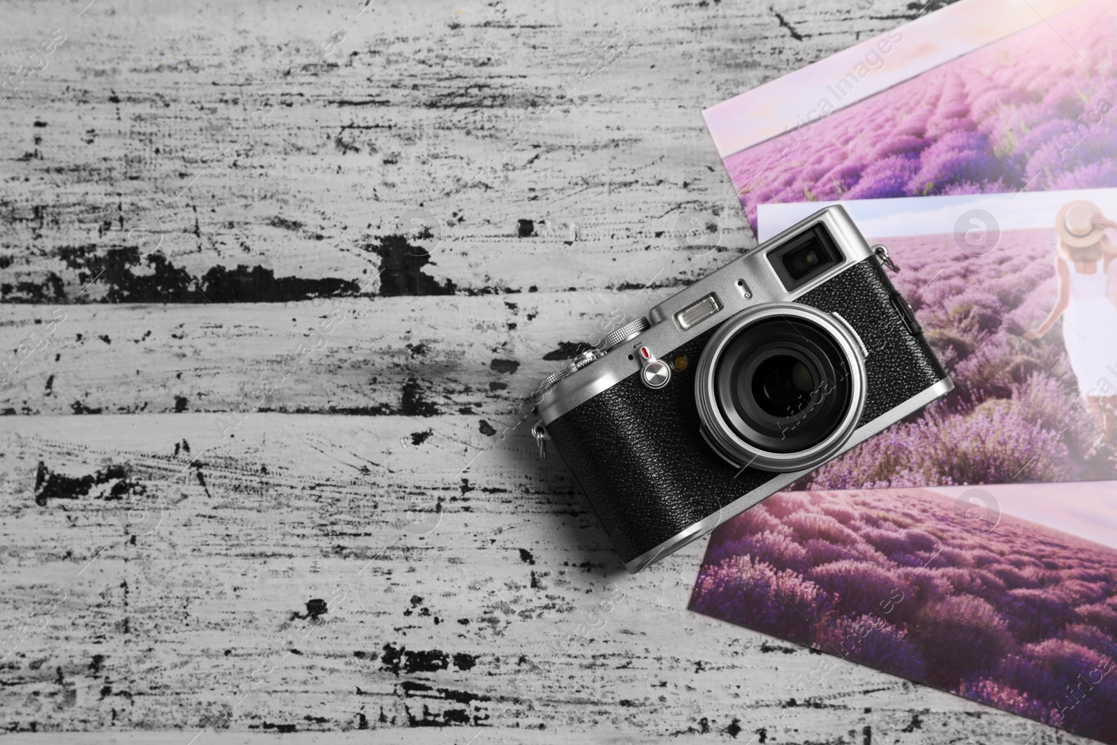 Photo of Vintage photo camera and beautiful printed pictures on rustic table, flat lay. Creative hobby