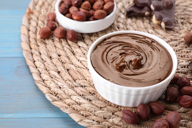 Bowl with tasty paste, chocolate pieces and nuts on light blue wooden table