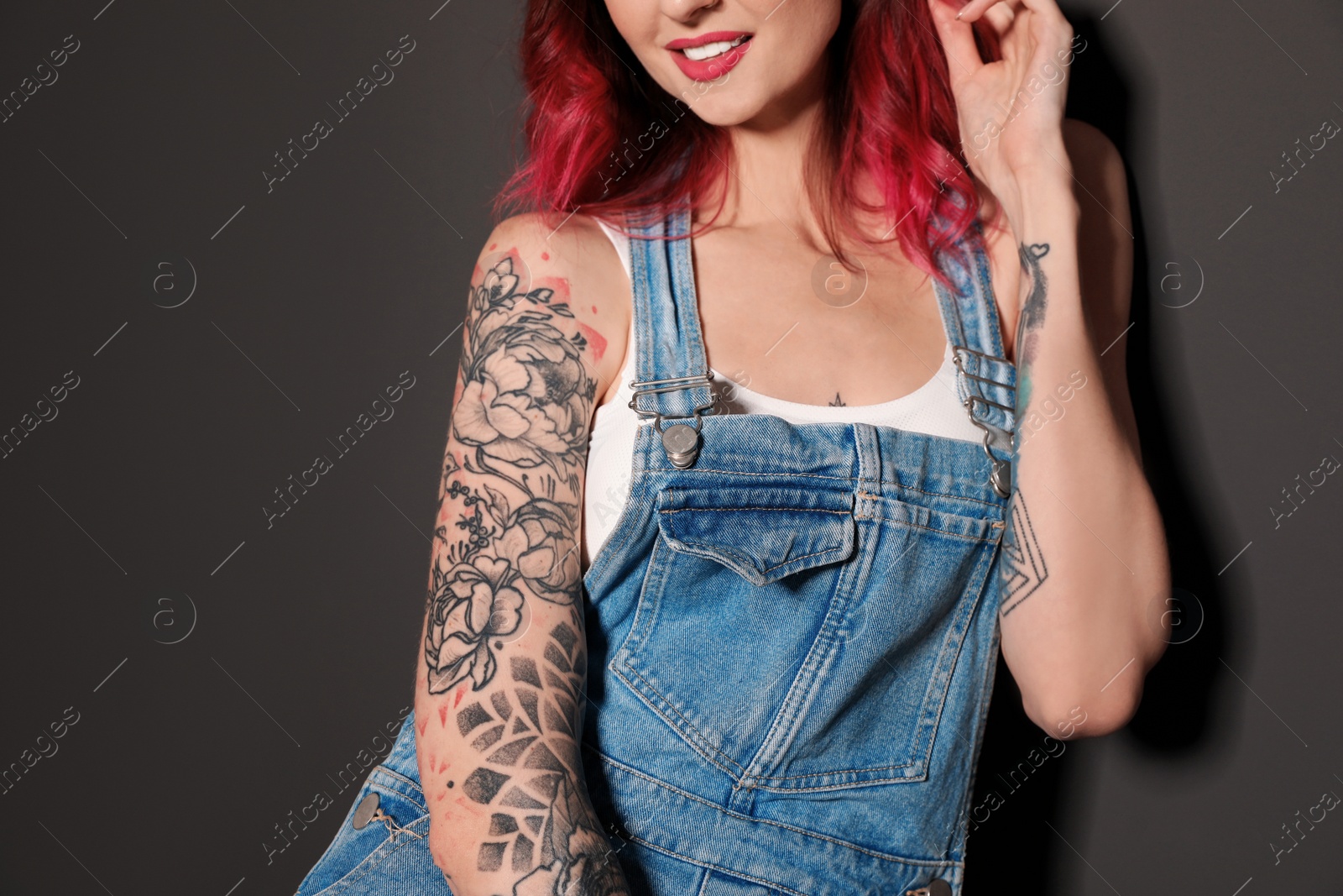 Photo of Beautiful woman with tattoos on body against black background, closeup