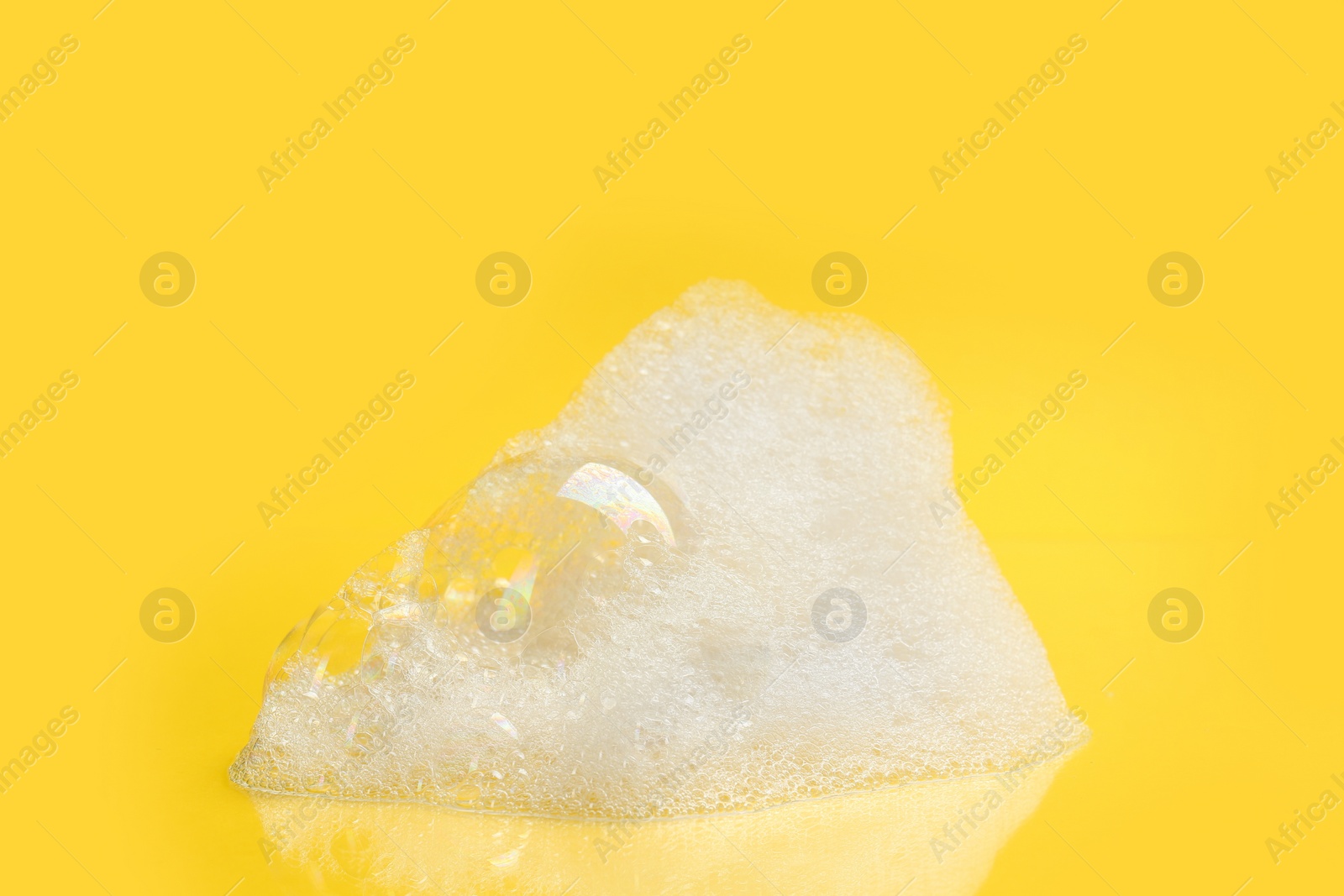 Photo of Drop of fluffy bath foam on yellow background