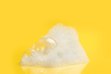 Photo of Drop of fluffy bath foam on yellow background