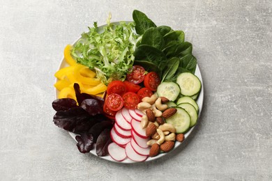 Balanced diet and vegetarian foods. Plate with different delicious products on grey table, top view