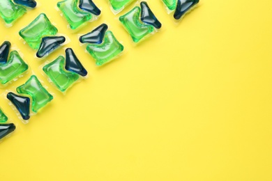 Photo of Laundry capsules on yellow background, flat lay. Space for text