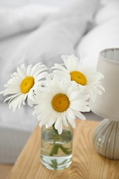 Photo of Bouquet of beautiful daisy flowers and lamp on nightstand in bedroom