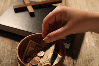 Photo of Donate and give concept. Woman putting coin into bowl with money at table, closeup