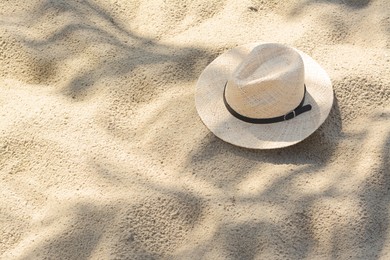 Stylish straw hat on sand outdoors, space for text