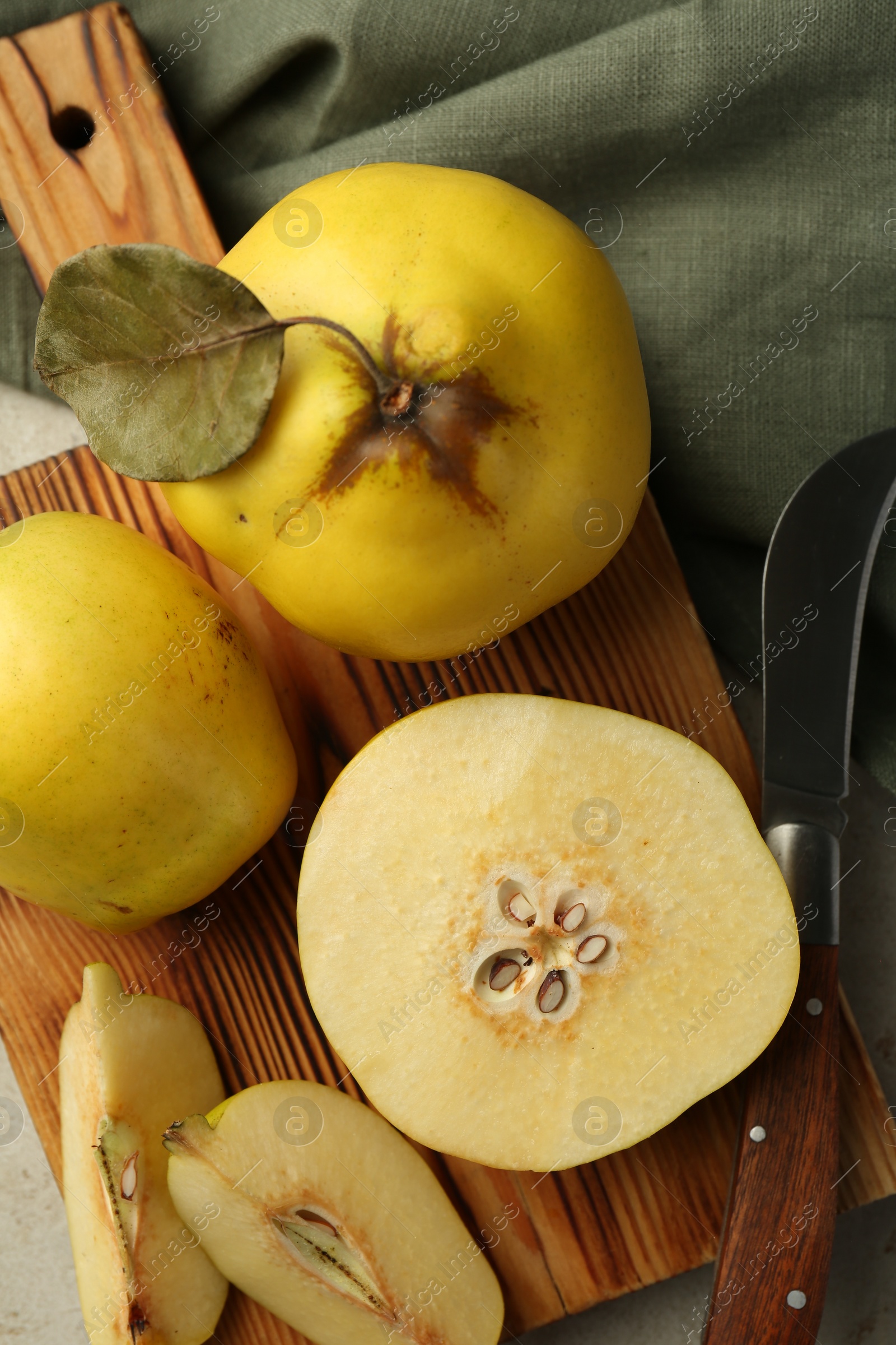 Photo of Tasty ripe quince fruits and knife on grey table, flat lay