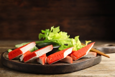 Photo of Fresh crab sticks with lettuce served on wooden table