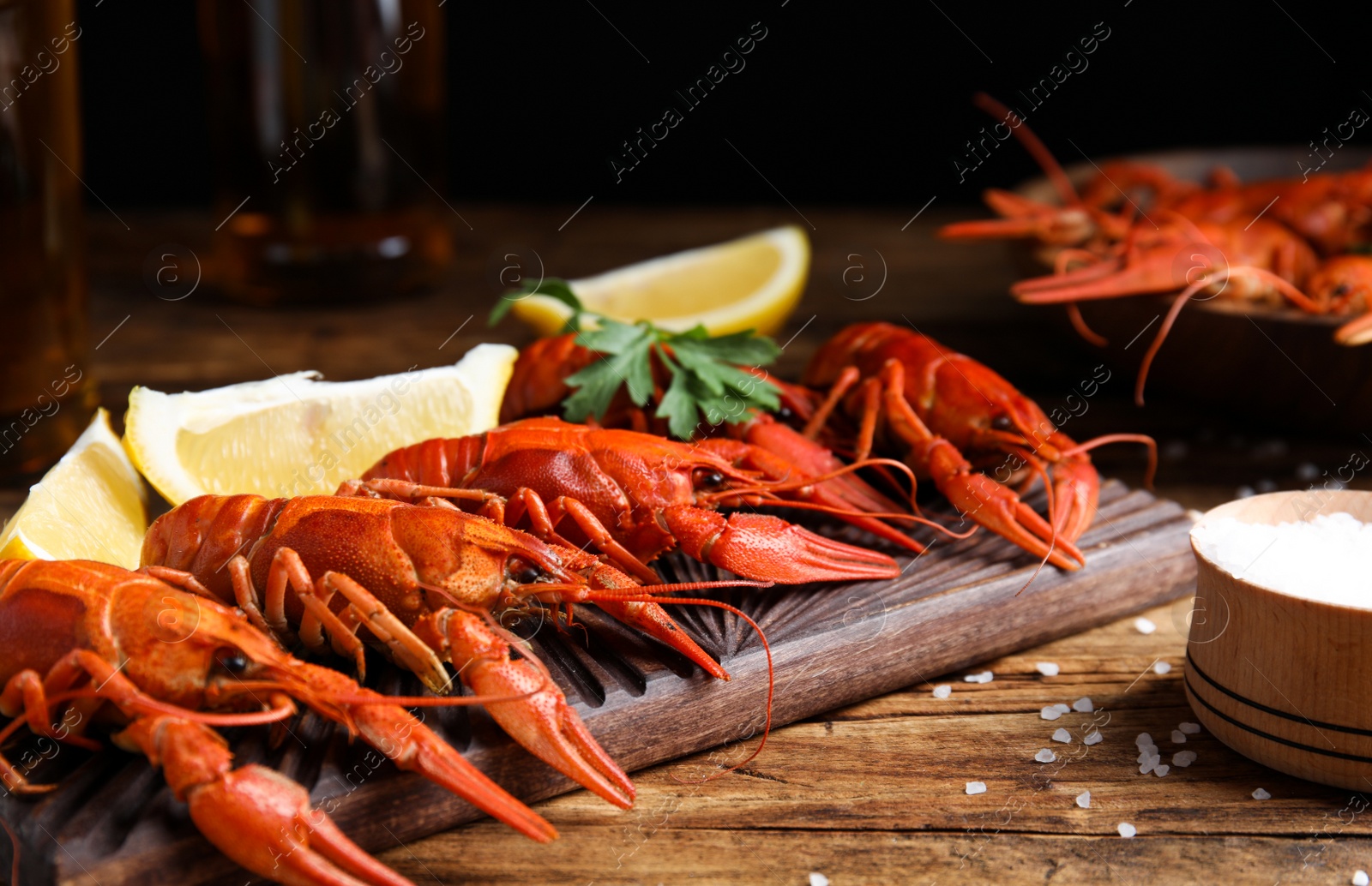 Photo of Delicious red boiled crayfishes on wooden table, closeup