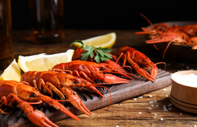 Delicious red boiled crayfishes on wooden table, closeup