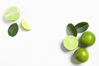 Photo of Fresh ripe limes and leaves on white background, flat lay. Space for text
