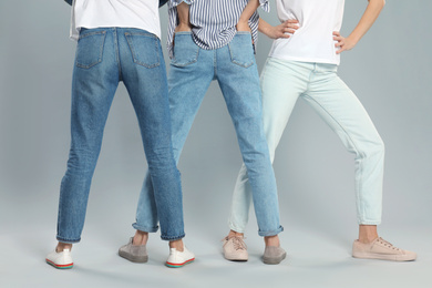 Photo of Group of young women in stylish jeans on grey background, closeup
