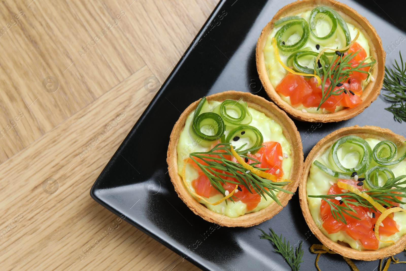 Photo of Delicious canapes with salmon on wooden table, top view