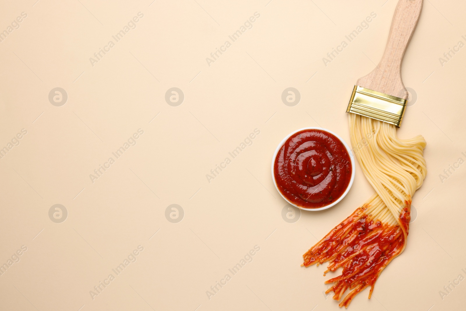 Photo of Brush painting with spaghetti dipped in ketchup on beige background, flat lay. Space for text. Creative concept