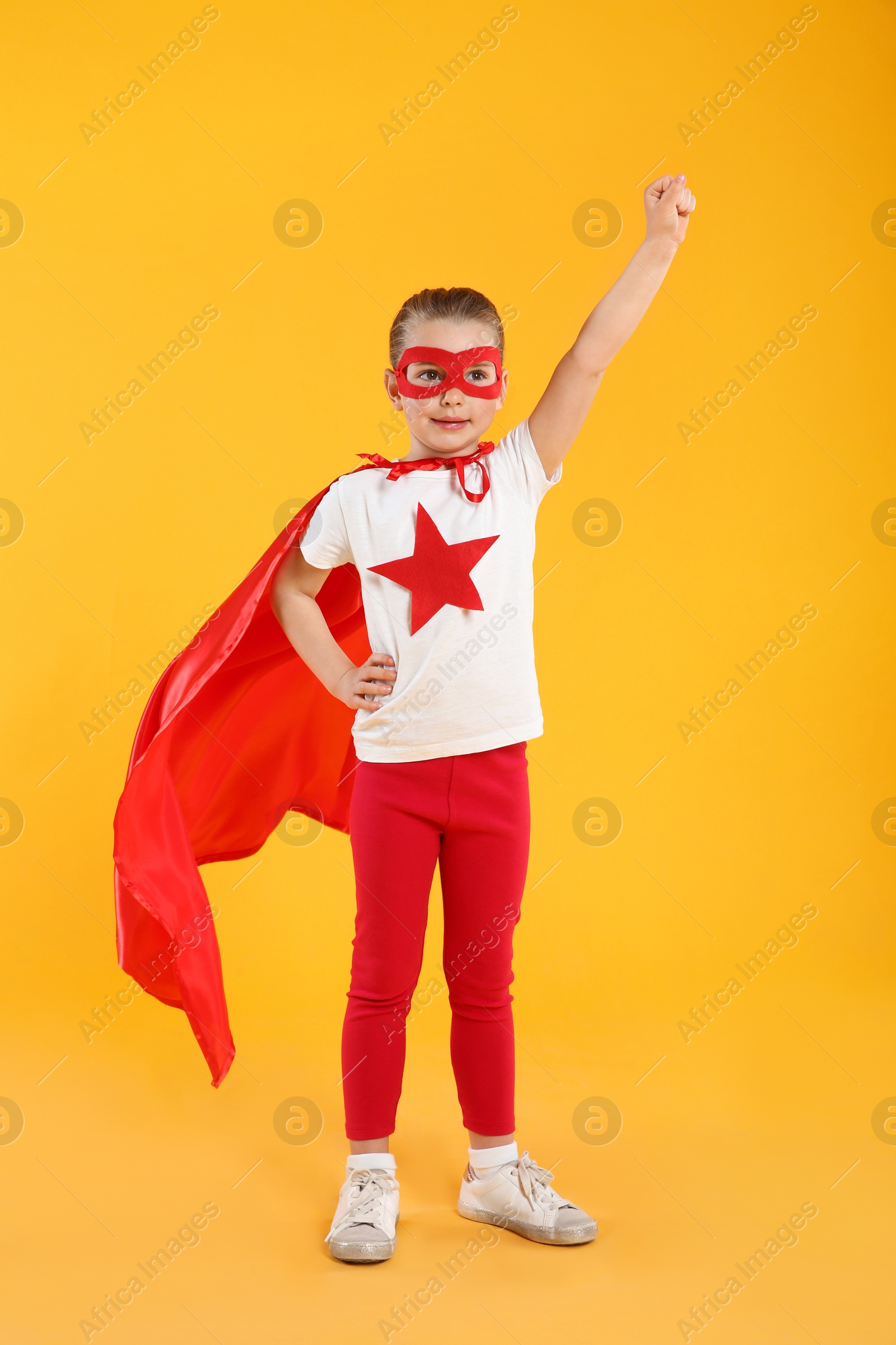 Photo of Little girl in superhero costume on yellow background