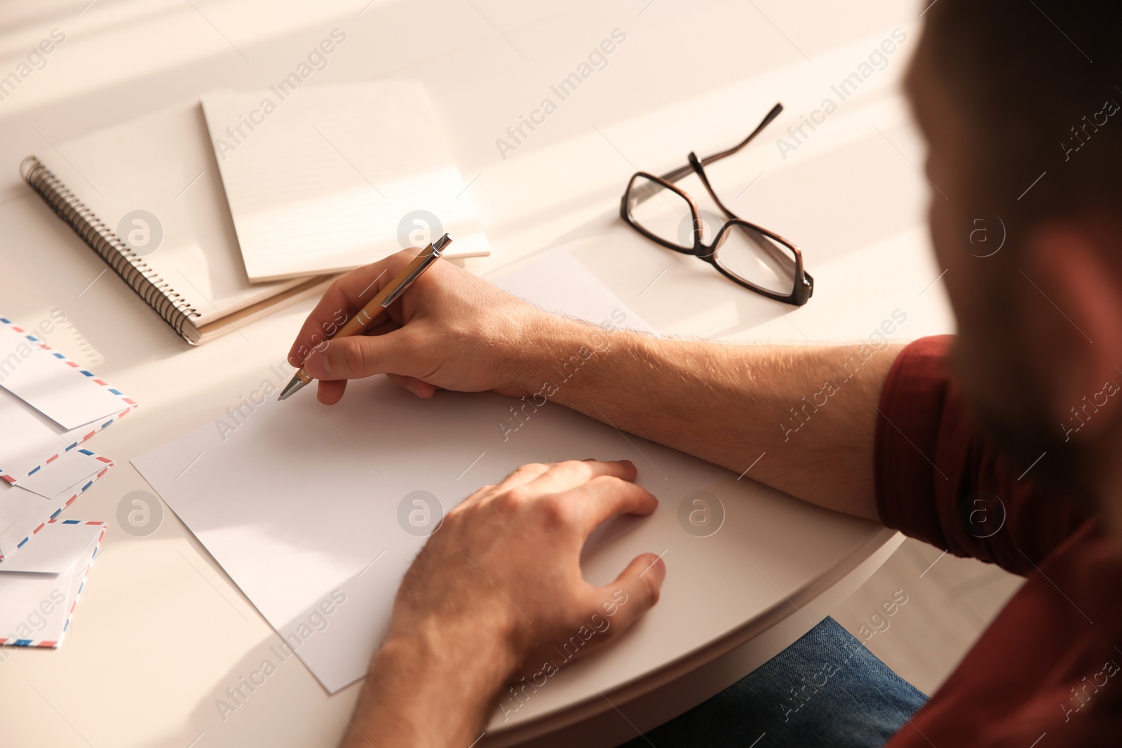 Photo of Man writing letter at white table, closeup