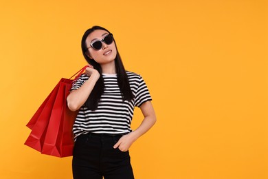 Photo of Smiling woman with shopping bags on yellow background. Space for text