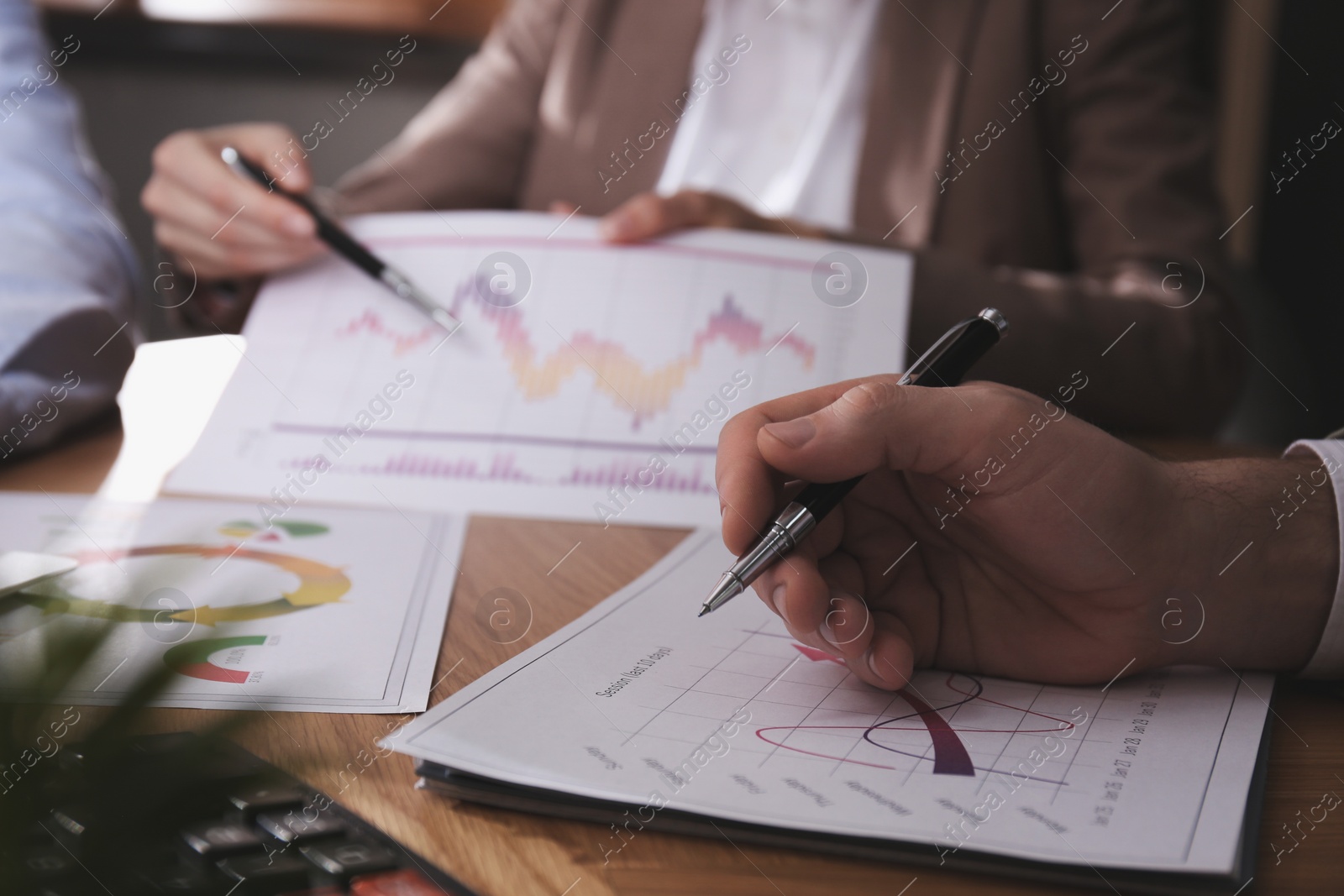 Photo of Business people working with charts and graphs at table in office, closeup. Investment analysis