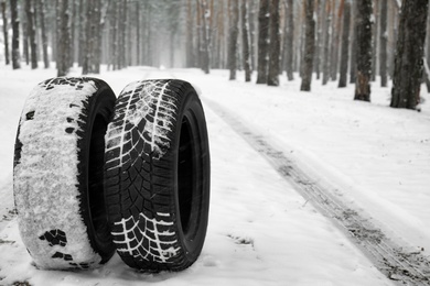 Photo of New winter tires on fresh snow near forest. Space for text