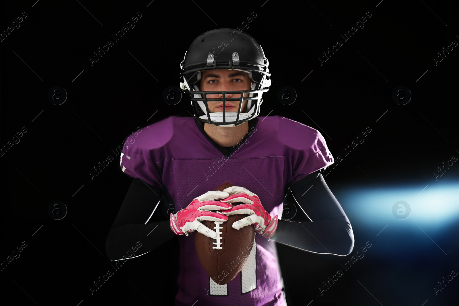 Photo of American football player with ball on dark background