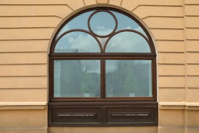 Photo of Wall of beige stone building with beautiful wooden arch window