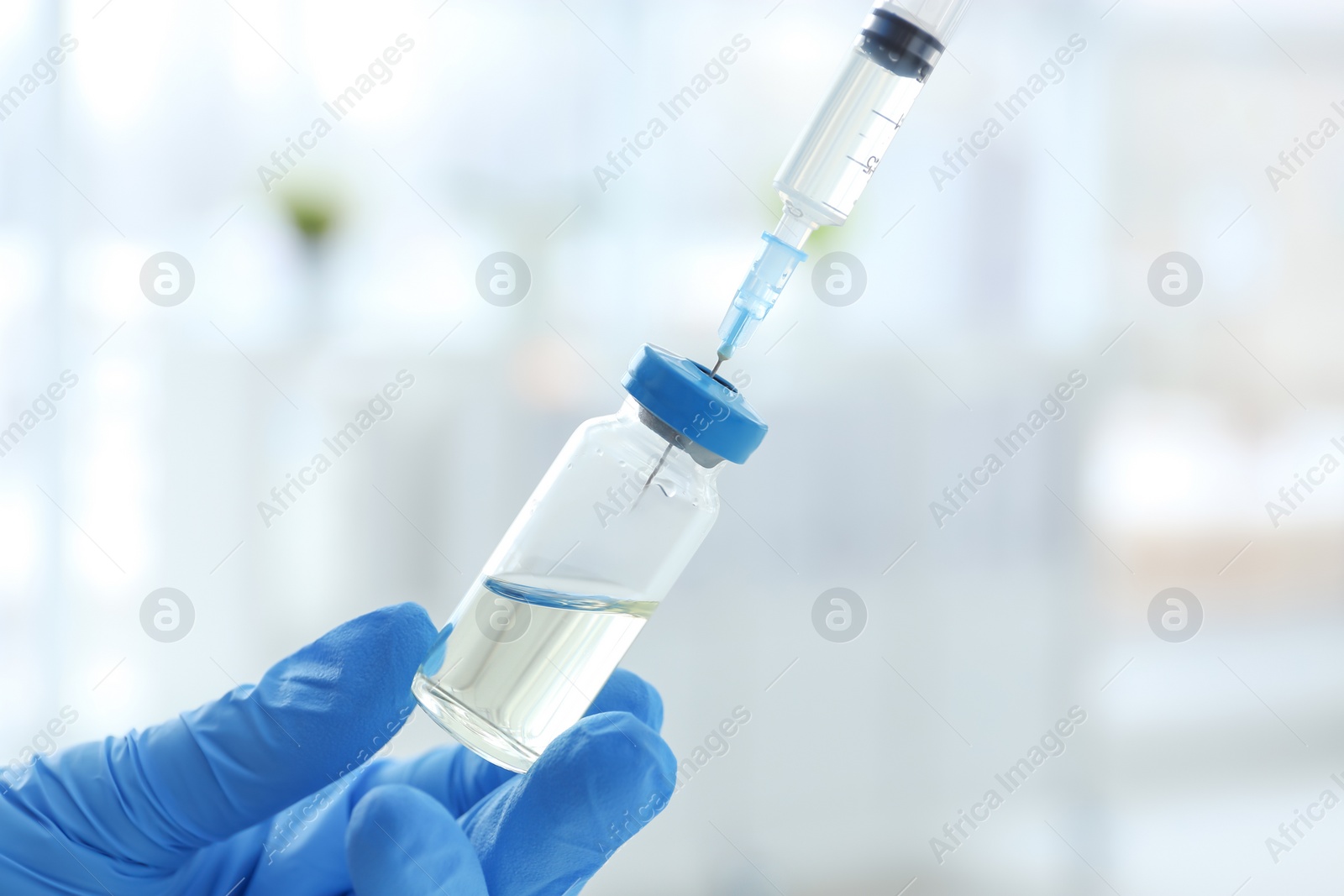 Photo of Doctor with syringe and medicine for vaccination on blurred background