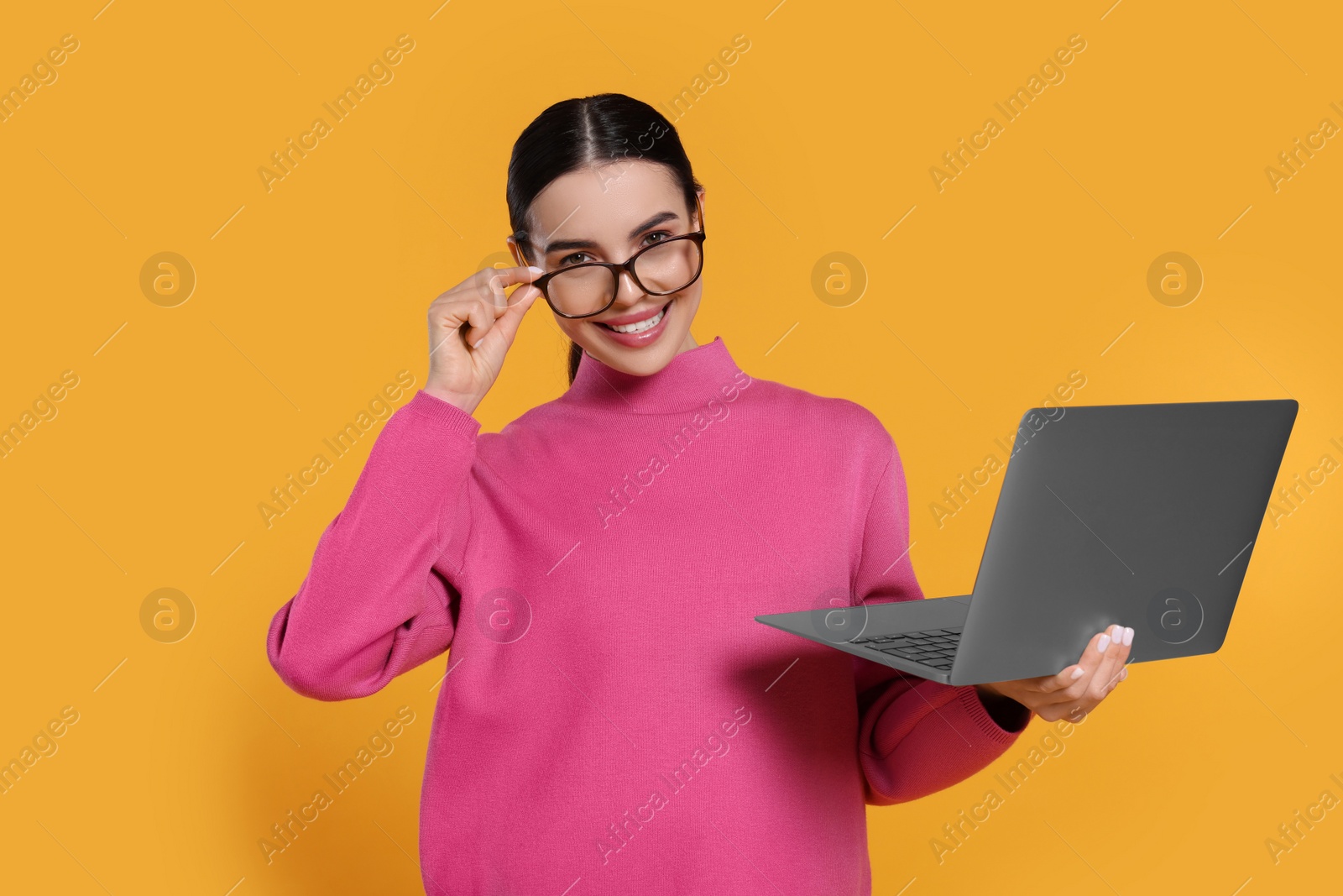 Photo of Happy woman with laptop on orange background