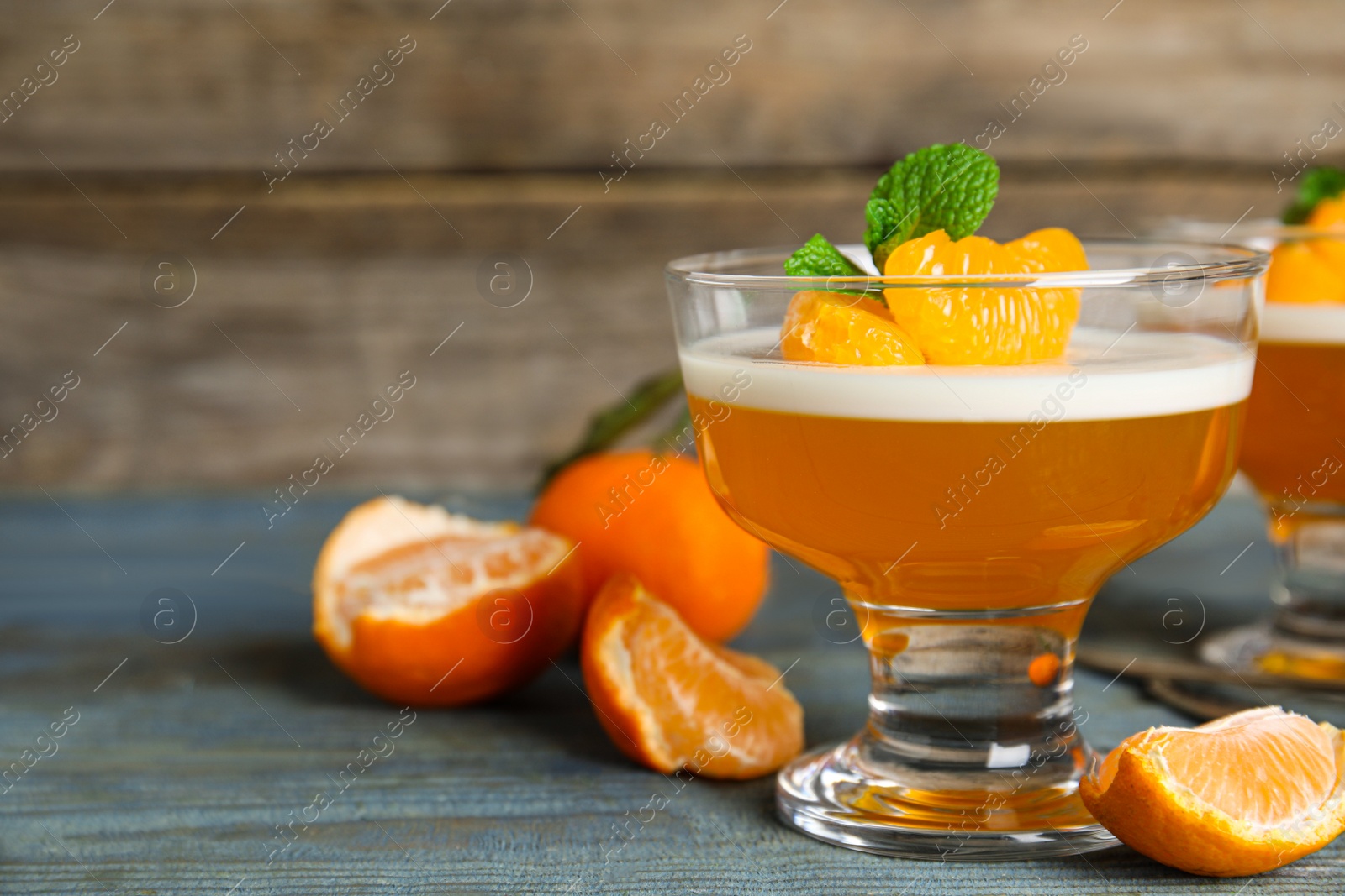 Photo of Delicious tangerine jelly and fresh fruits on light blue wooden table, closeup