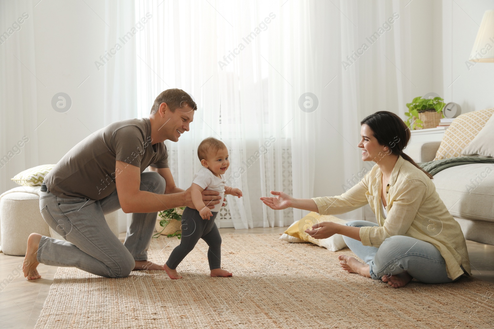 Photo of Parents supporting their baby daughter while she learning to walk at home