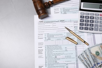 Photo of Tax return forms, gavel, money and calculator on grey table, top view. Space for text