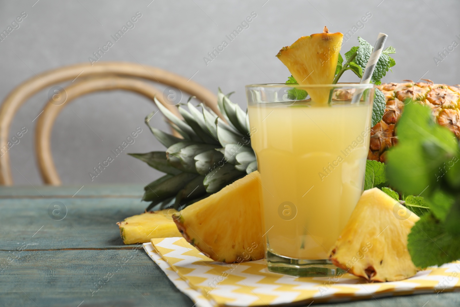 Photo of Delicious pineapple juice and fresh fruit on blue wooden table. Space for text