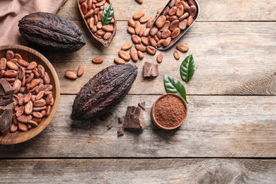 Photo of Flat lay composition with cocoa beans, chocolate pieces and pods on wooden table