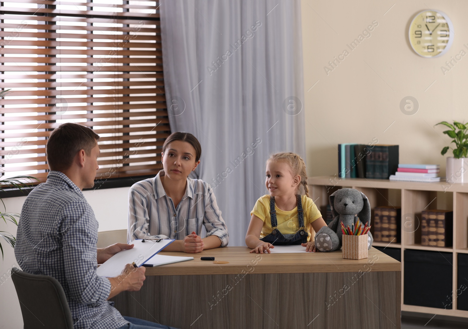 Photo of Child psychotherapist working with little girl and her mother in office