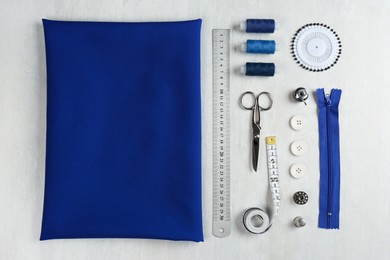 Photo of Different sewing supplies and fabric on light table, flat lay
