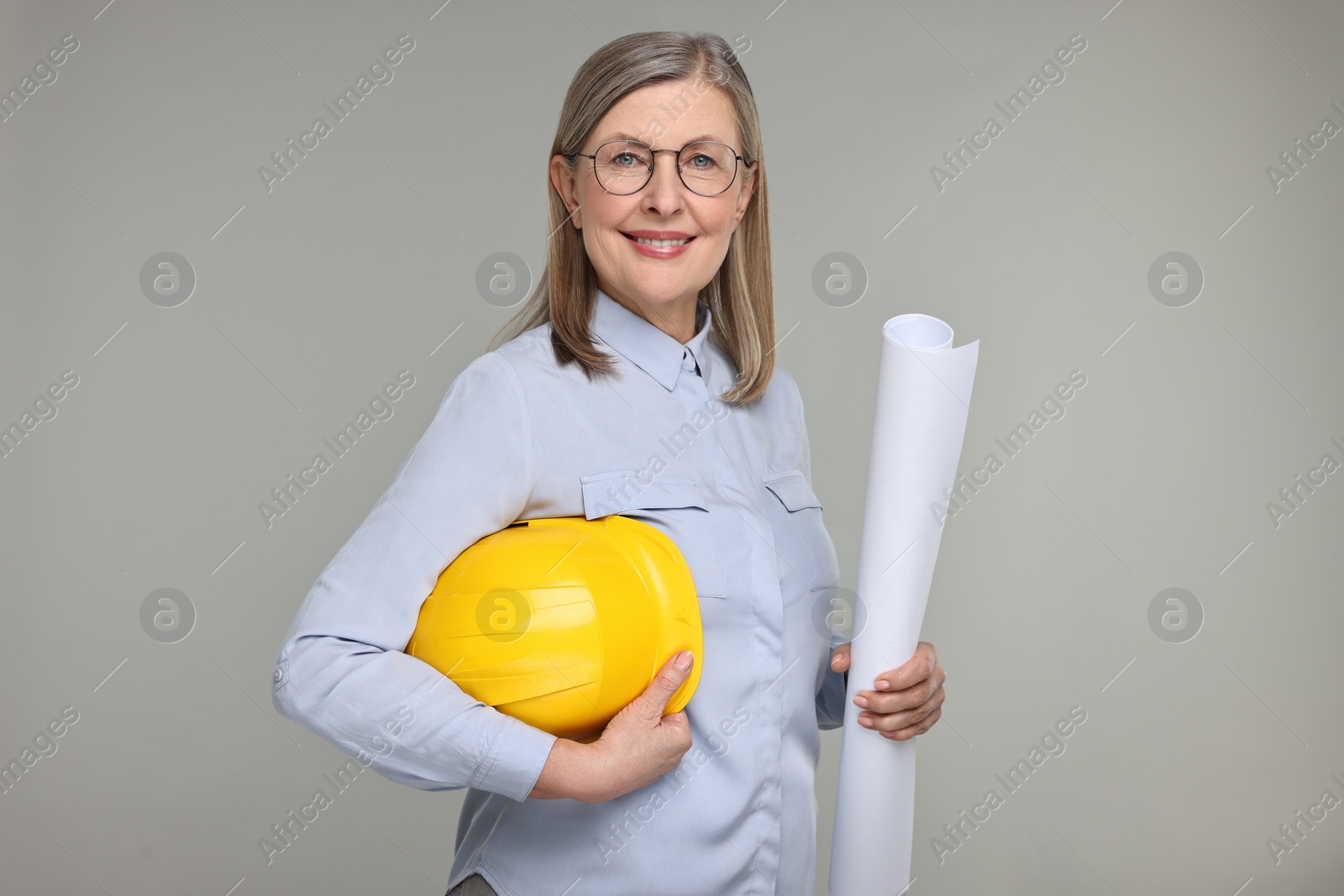 Photo of Architect with hard hat and draft on grey background
