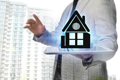 Image of Double exposure of real estate agent with house illustration over tablet and apartment building